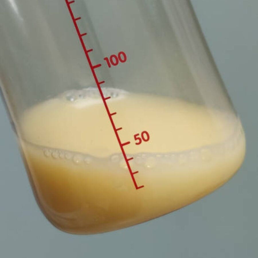 small clear bottle with less than 1 ounce or 30mL of yellow colored colostrum, tilted to the side